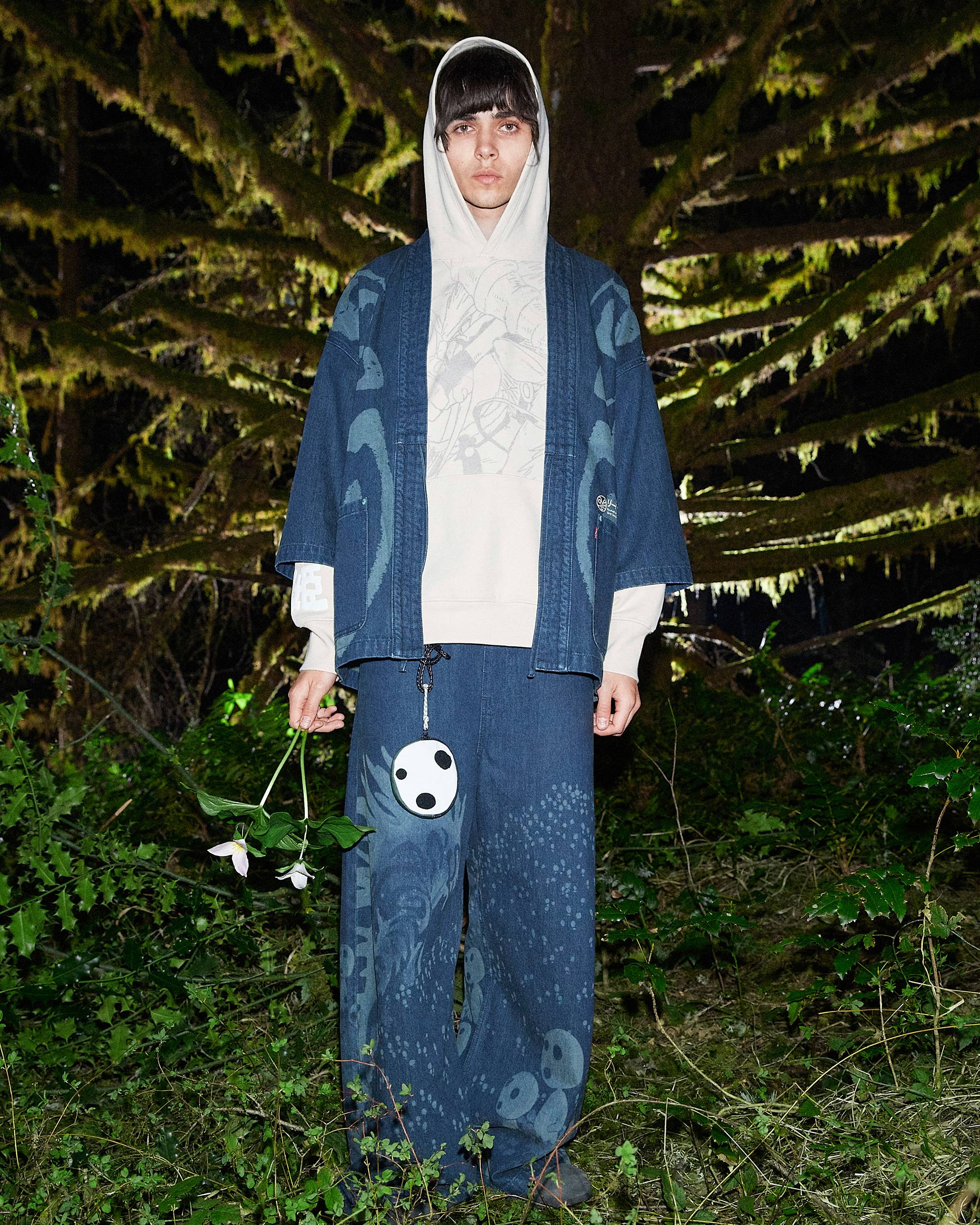 Image of person wearing Levi's® x Princess Mononoke collection pieces and posing in dramatic forest setting