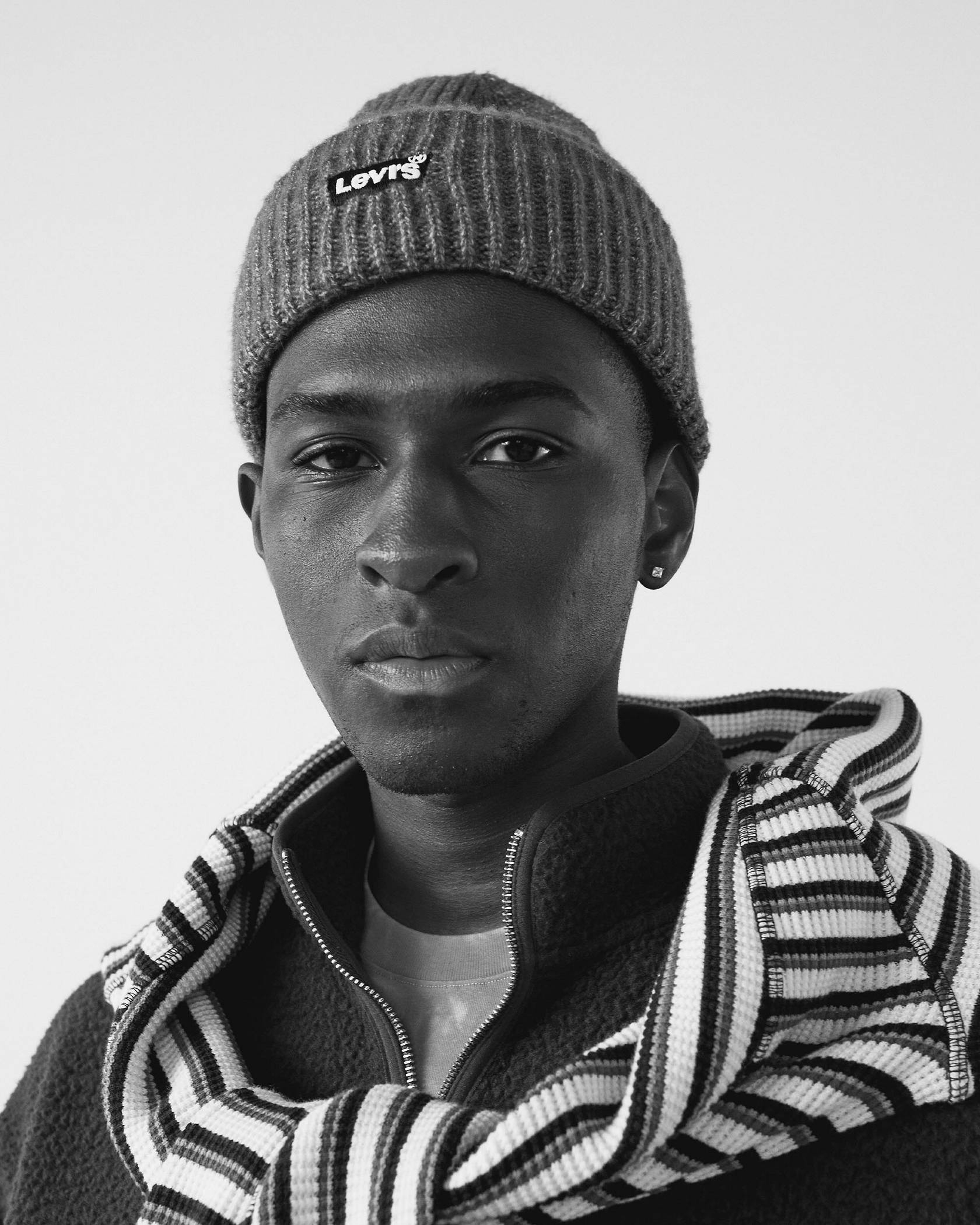 Black and white photo of model wearing a logo beanie