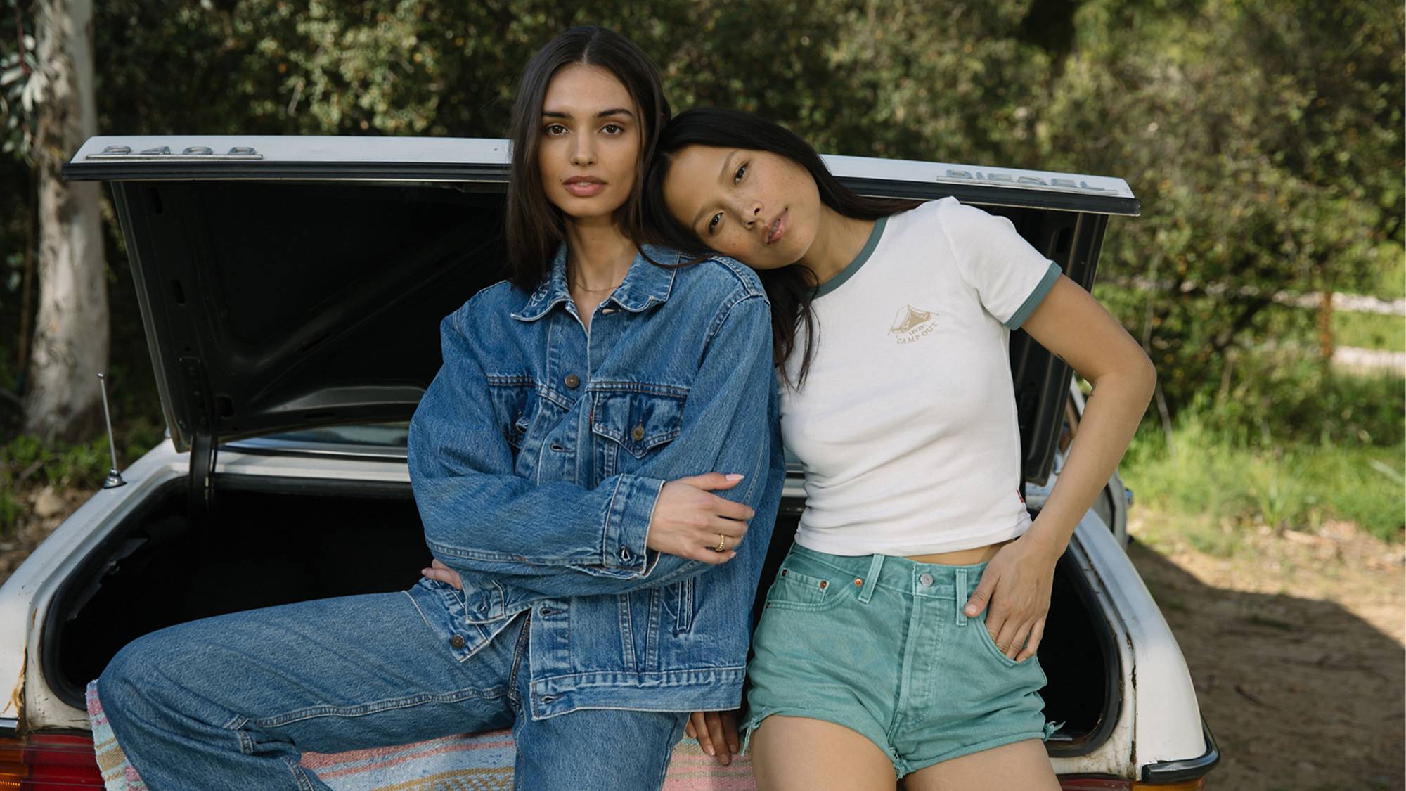 Models leaning against a car in Trucker Jacket, 501® Jeans, 501® Shorts and Mini Ringer Tee