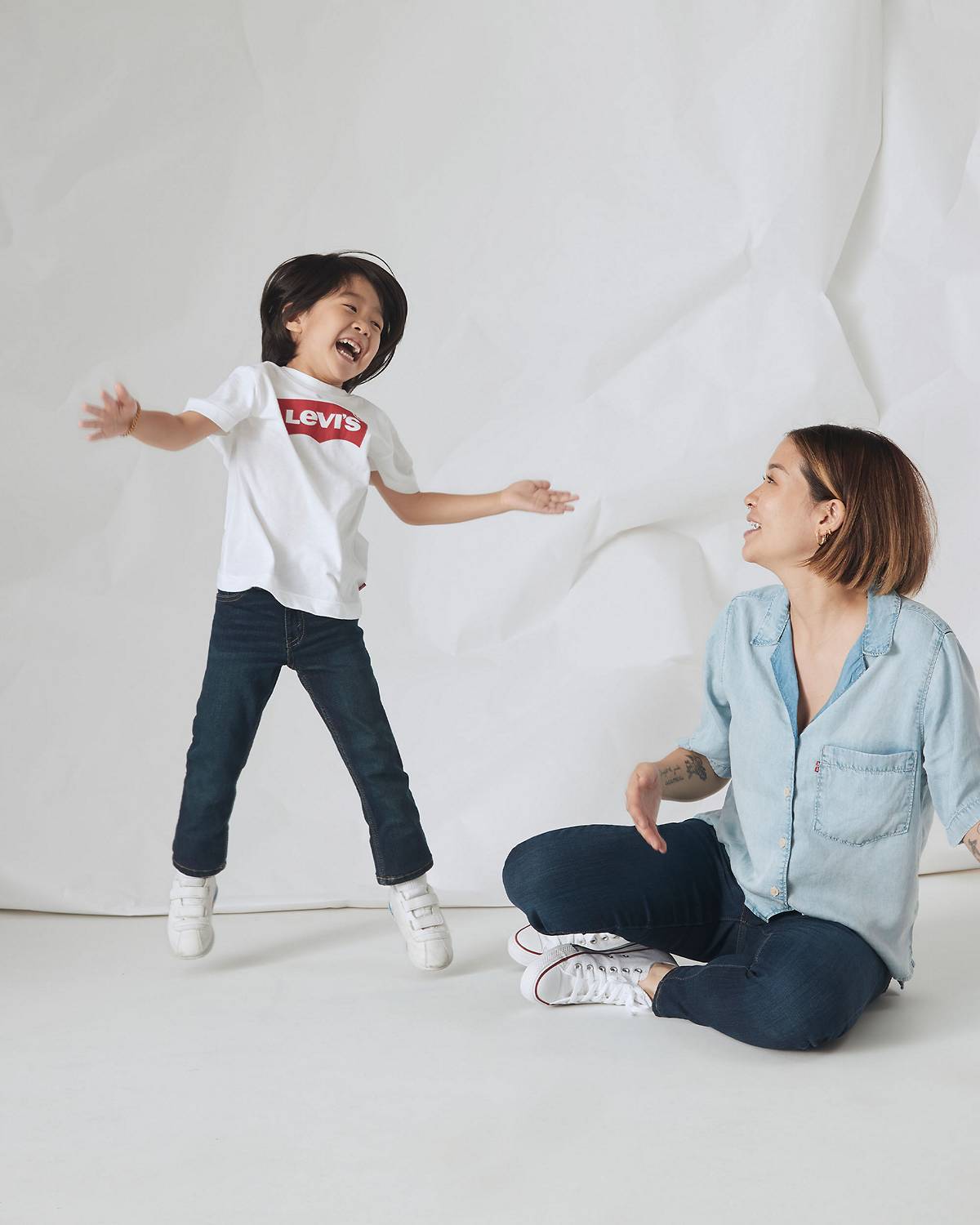Rotating imagery of kid jumping next their mom in assorted Levi's styles
