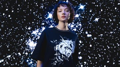 Image of woman wearing futuristic clothing and posing against dark and starry background