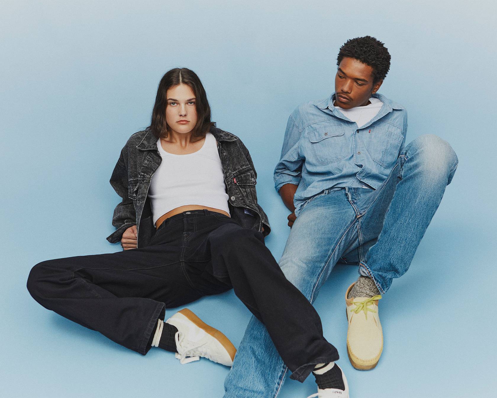Models on a light blue background in black and medium wash 501® Jeans