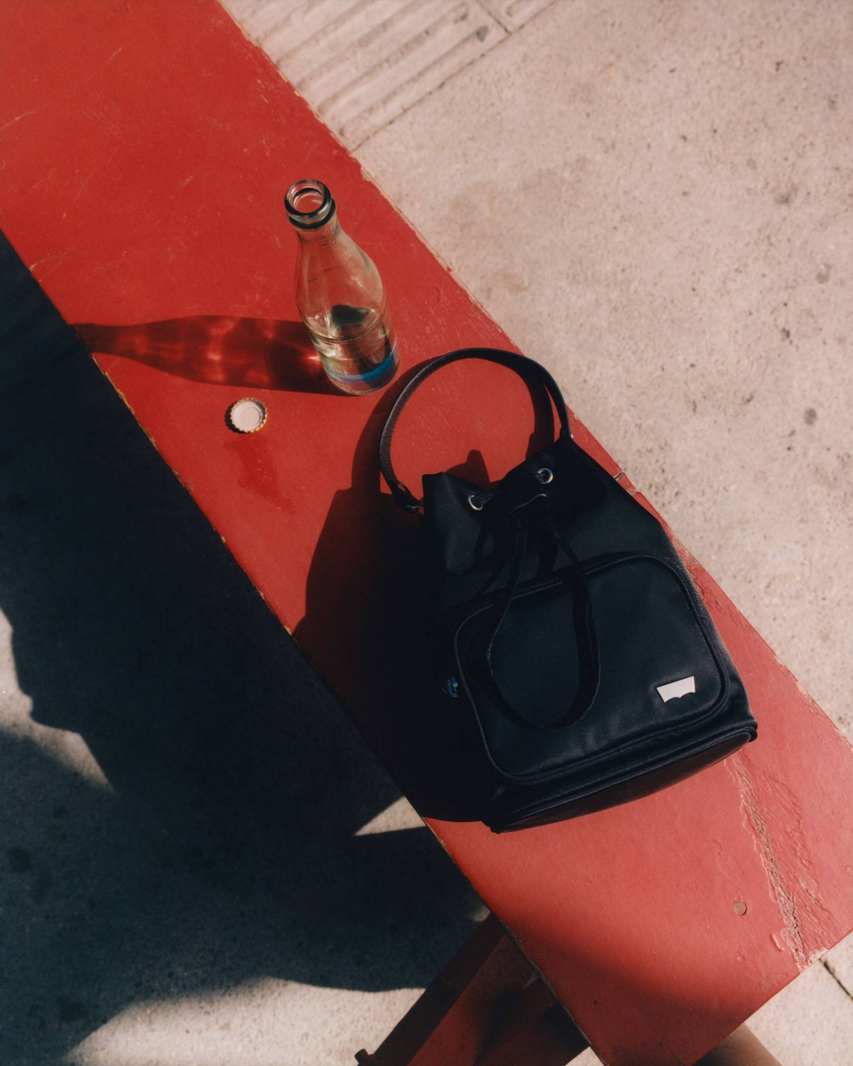 Black bucket bag against a red bench