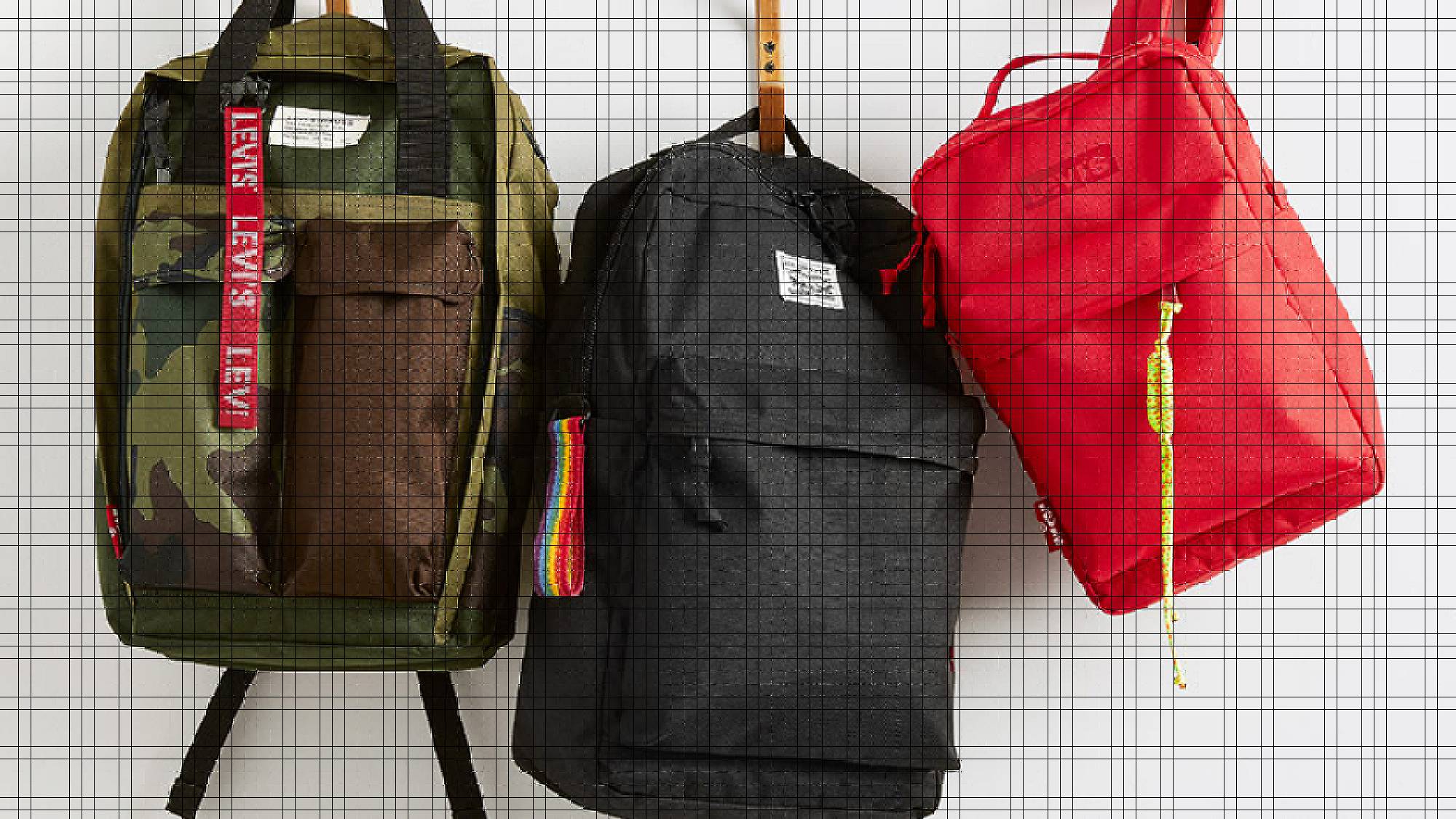 Three backpacks hanging on a white wall