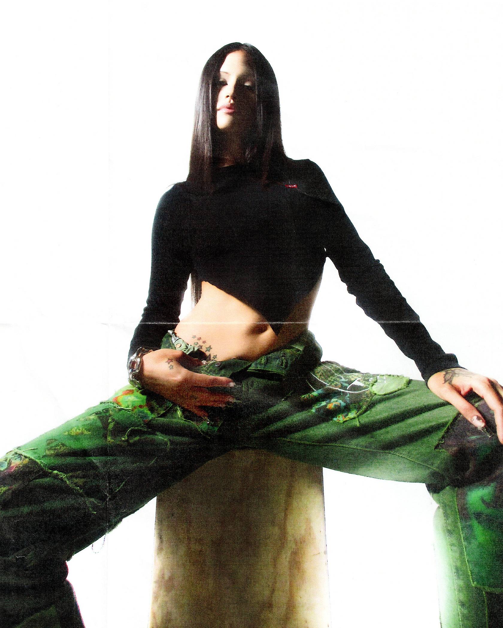 Model in a black cropped asymmetrical turtle neck and the green wash collab jeans
