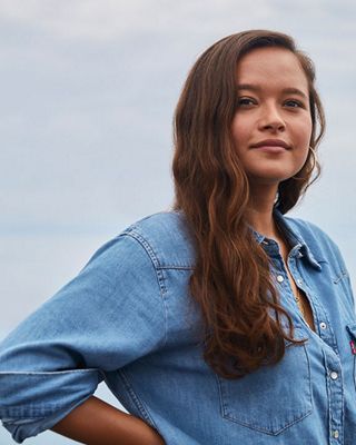 Three photos, the first shows the back pockets of Melati's Levi jean shorts, the second photo is a portrait shot of Melati in a Levi's button up standing with her hands on her hips, and the third photo shows Melati standing in front of the ocean laughing wearing Levi jean shorts and a Levi's button up shirt