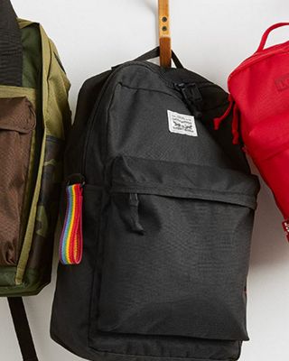 Three backpacks hanging on a white wall