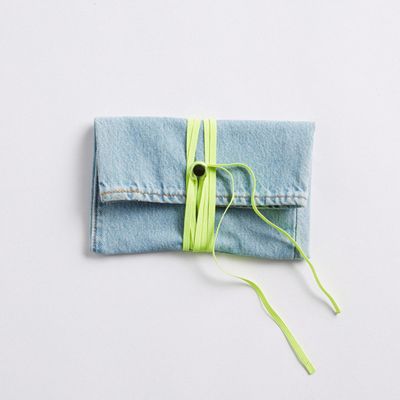 Image of the finished DIY denim wallet with a neon green cord and black button closure.