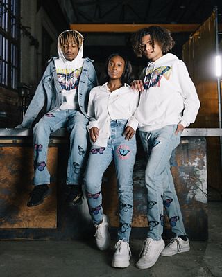 Three people posted up posing wearing light wash jeans with butterflys.
