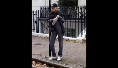 On the left is a video of Claire Rose standing against a sign then walking off screen wearing a black New York Yankees baseball cap, gray sweatshirt, black puffer, gray jeans, and white sneakers. On the right is her wearing the same outfit sitting on the curb.