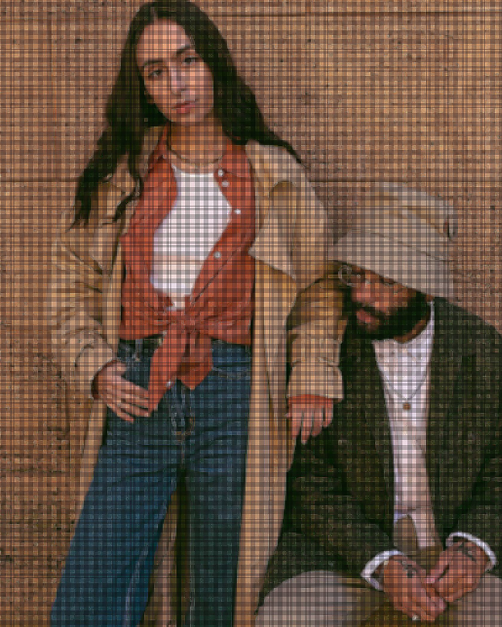 Image of Adeline Hocine and Paul Bellas standing against a brown wall. Adeline is wearing a tan colored trenchcoat, orange blouse, white tank top and blue denim jeans while Paul is wearing a tan colored bucket hat, green camo jacket, white button down shirt and tan colored cargo pants.