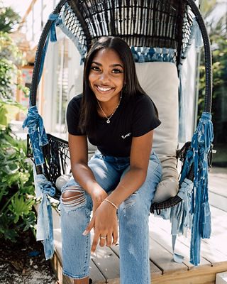 TikToker Gabby Morrison sits on a denim floating chair while wearing a black Levi's® tee shirt and Levi's® Future Finish light wash Wedgie jeans.