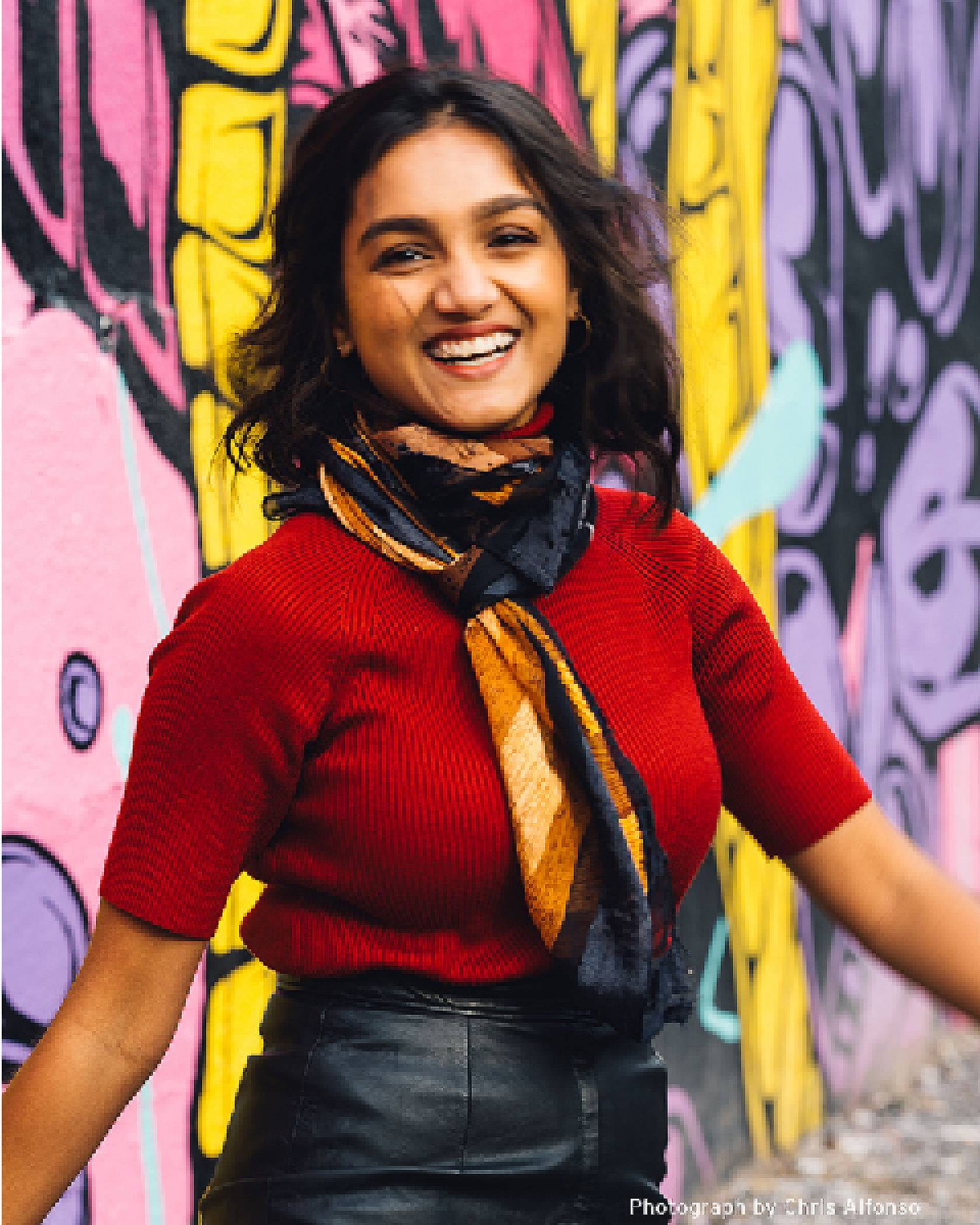 Portrait of Tahia Islam smiling in front of a wall of street art.