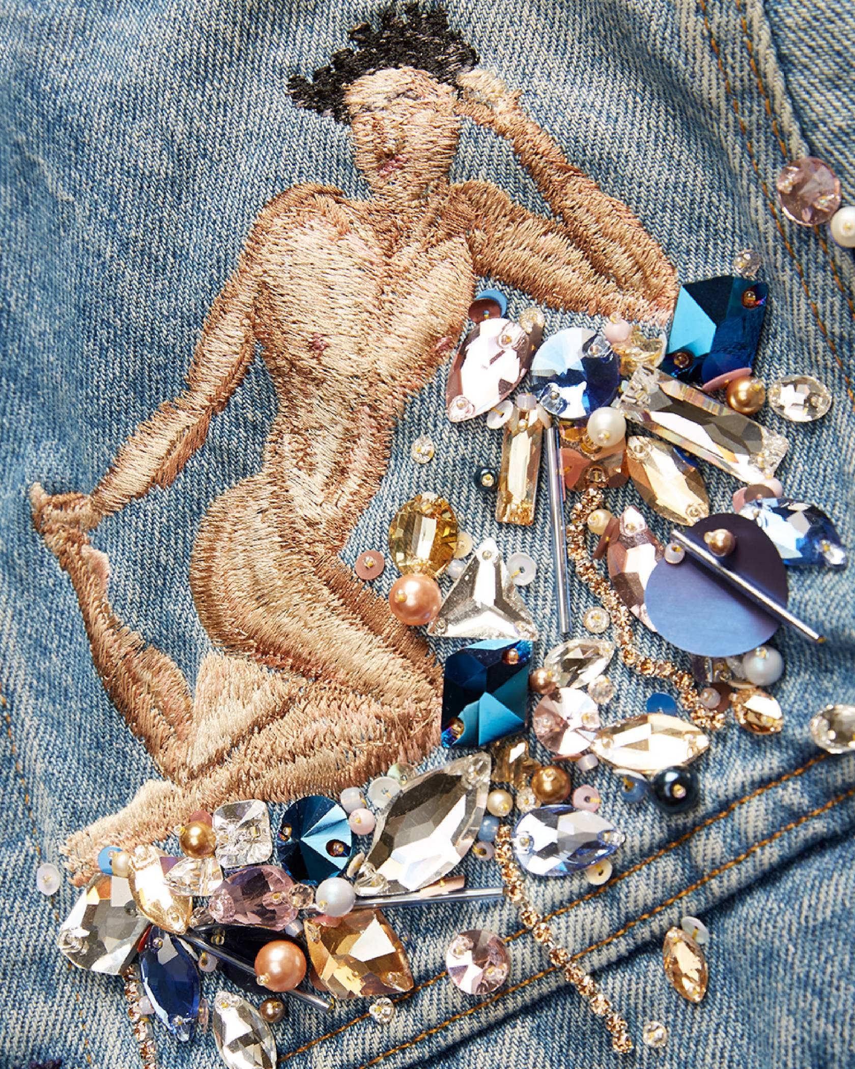 Close up image of the embroidery work of Michael-Birch Pierce for their collaboration. The embroidering shows an outline of a human lying on a bed of embroidered jewels on a trucker jacket.