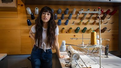 Bria Cheng leaning on a Tailor Shop table.