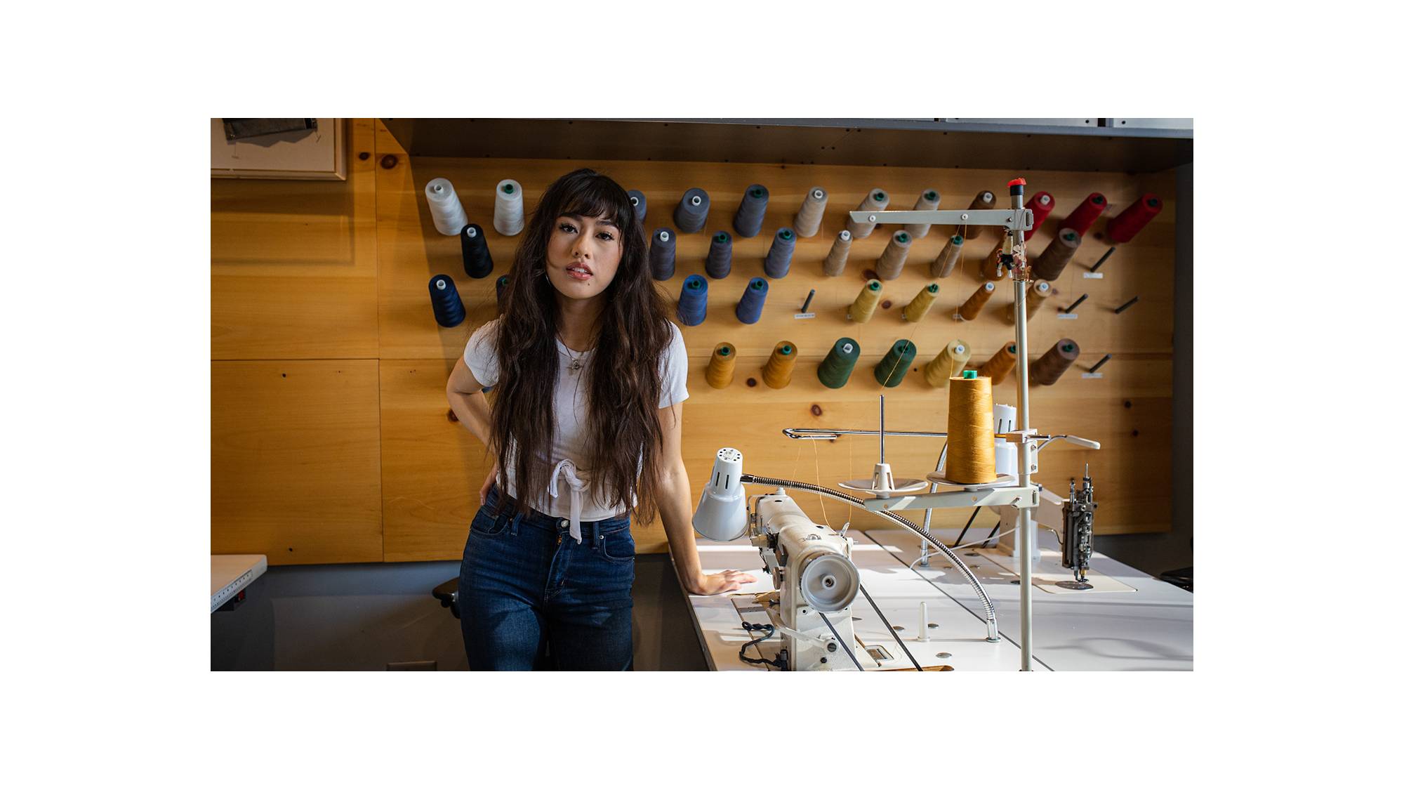 Bria Cheng leaning on a Tailor Shop table.