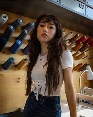 Bria Cheng leaning on a Tailor Shop table.