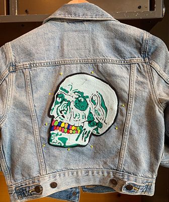 Light denim jacket with a skull on the back.