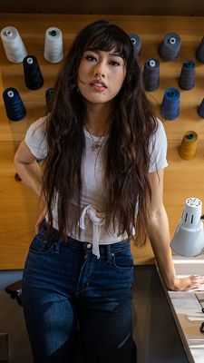 Bria Cheng leaning on a Tailor Shop table.