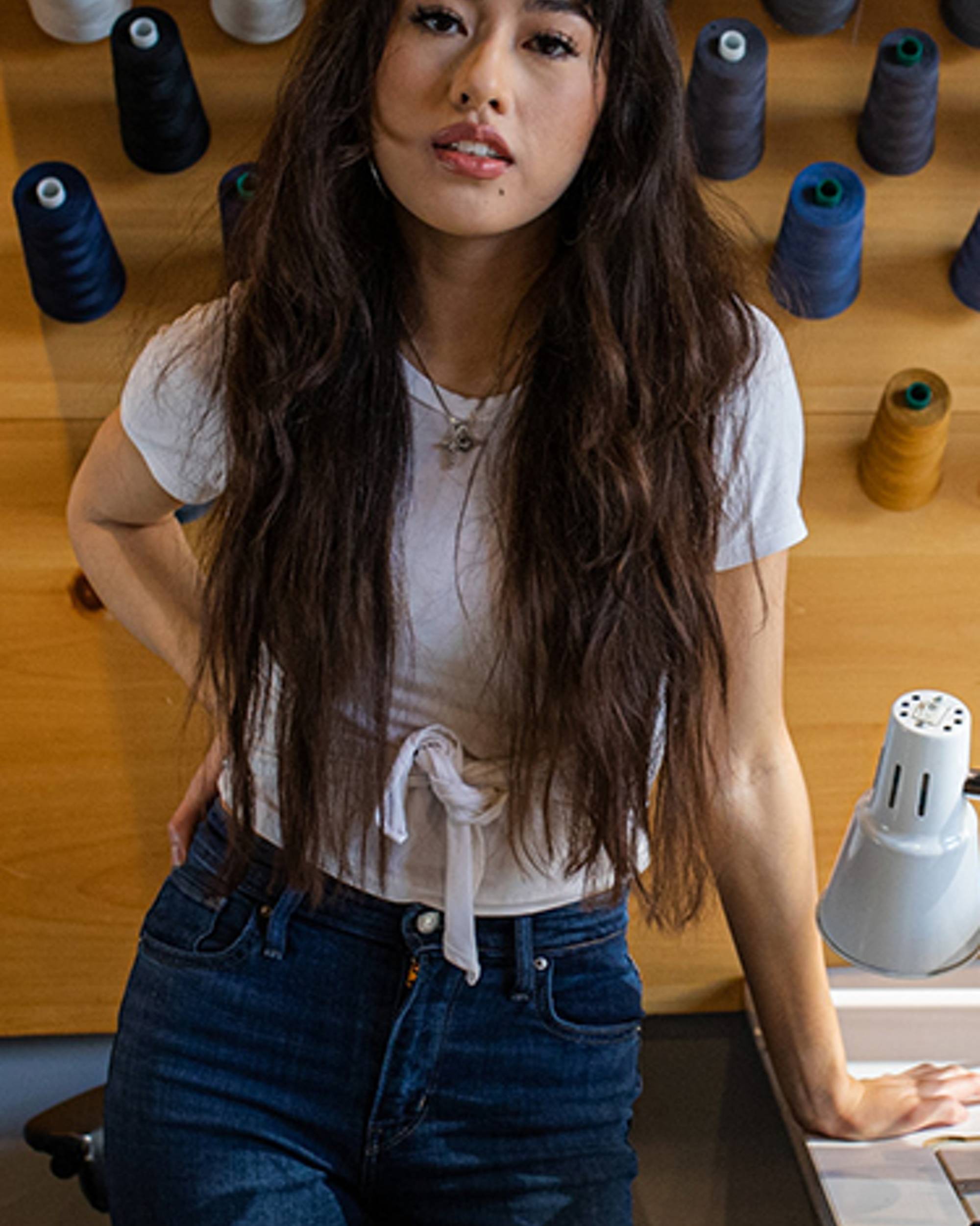 Bria Cheng leaning on a Tailor Shop table.