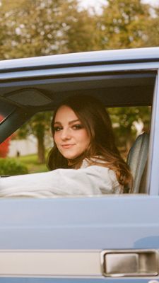 Mallory Kerman sitting in car with arm on window.