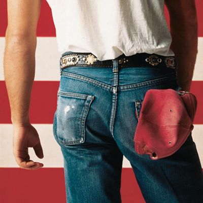 man standing in front of american flag with denim jeans and white shirt. facing backwards.