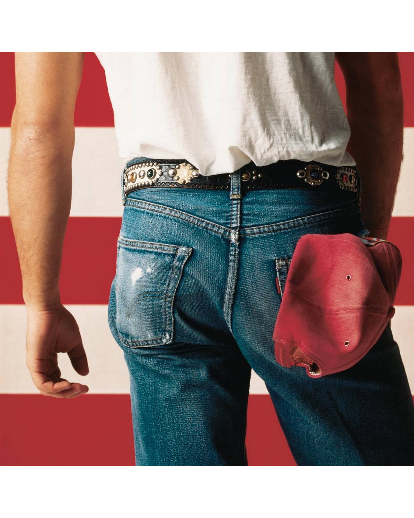 man standing in front of american flag with denim jeans and white shirt. facing backwards.