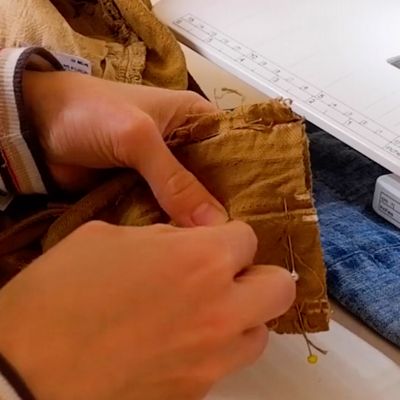 close up of hands sewing bottom of jeans