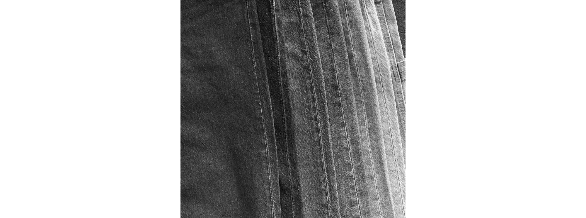 Black and white image of a stack of denim jeans.