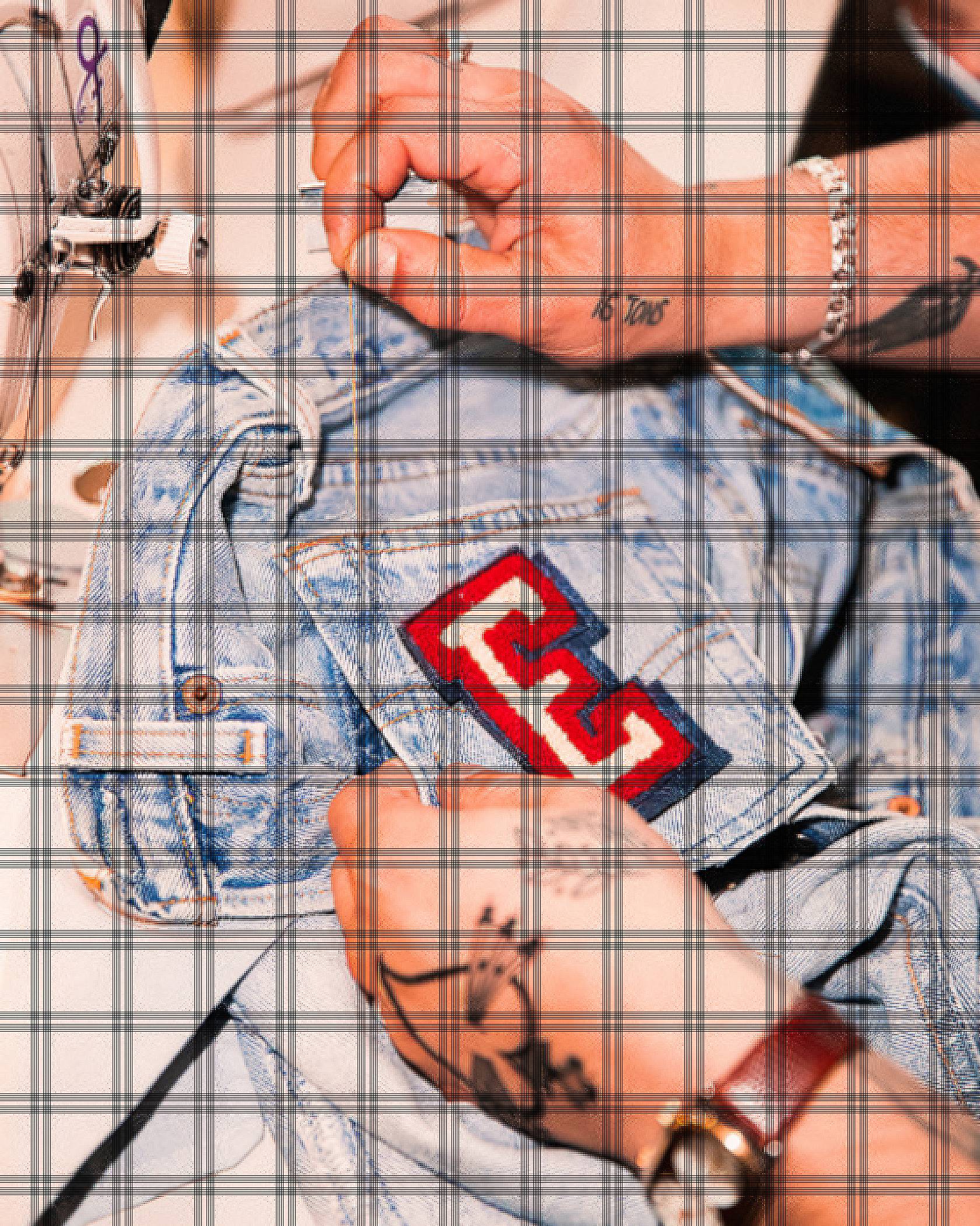 A patch of the Letter E held above a pair of jeans