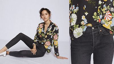 Woman wearing a floral black shirt with black jeans and white heels, laying down over white background.