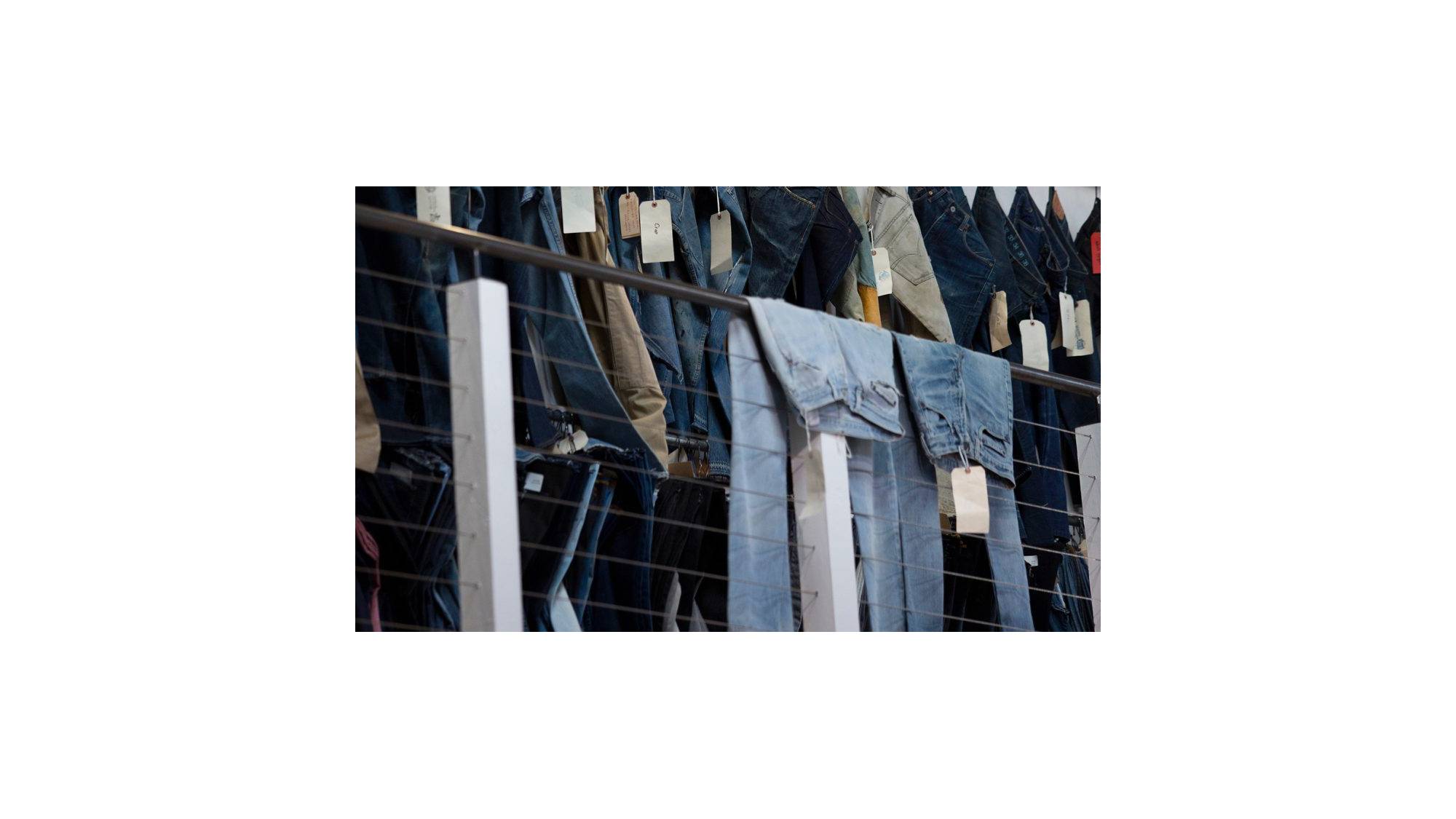 jeans hanging over railing with tags