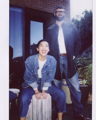 Photo of Victoria Cao and Michael Burch on the balcony of the Levi's Plaza. Victoria is seated and laughing, wearing a Levi's Trucker Jacket, white tee, and Levi's blue jeans. Michael is standing behind her, wearing an open indigo top over a white tee with Levi's blue jeans.