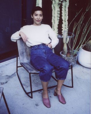 Polaroid photo of Victoria Cao sitting in a deck chair on the balcony of Levi's Plaza. She is wearing a white top and cropped Levi's blue jeans with mules.