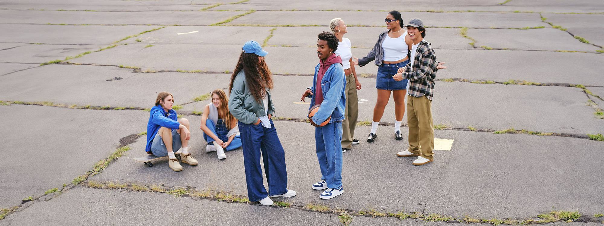 Large group shot of models outdoors in concrete lot wearing assorted denim looks and casual streetwear