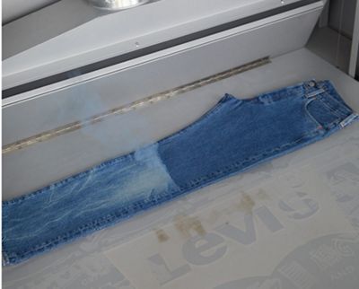 Dark pair of denim jeans being customized.