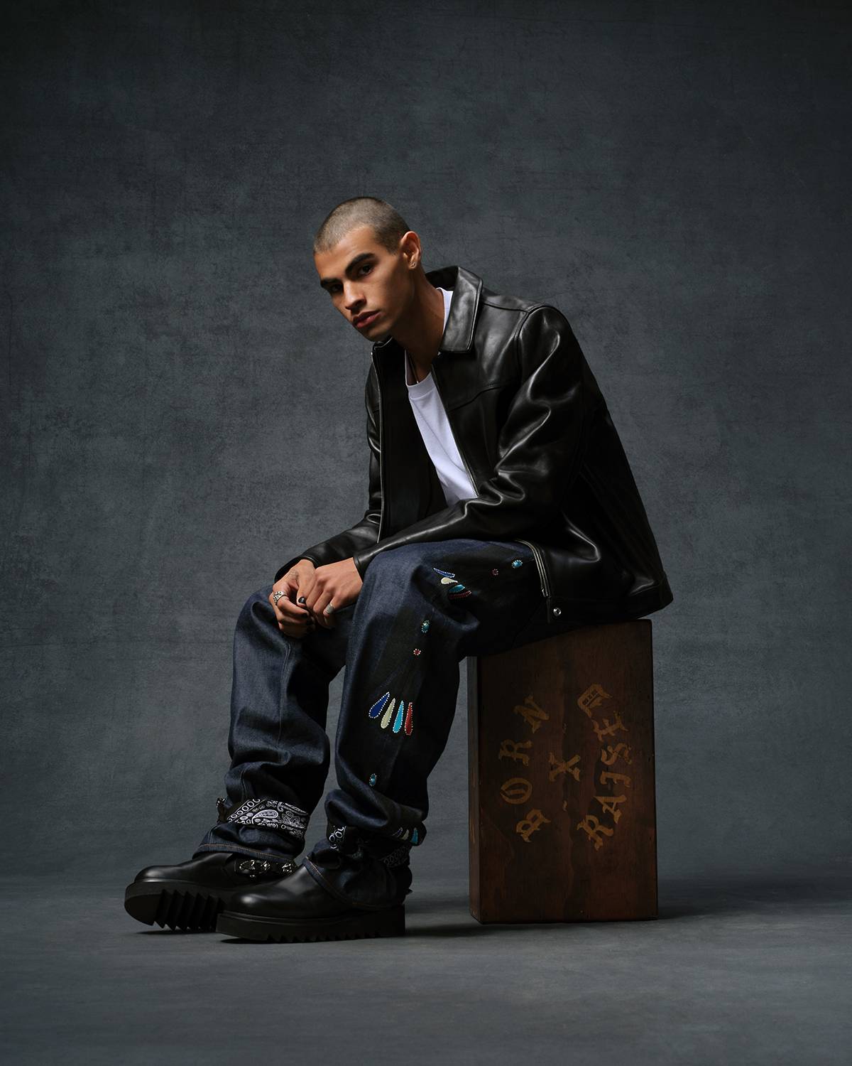 Image of model wearing a black leather jacket, white tee shirt and dark wash denim jeans from the Levi's® & Born x Raised capsule collection.
