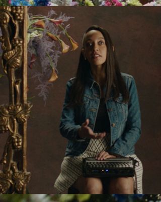 Image of Haben Girma speaking to a camera while surrounded by a golden frame and flowers.