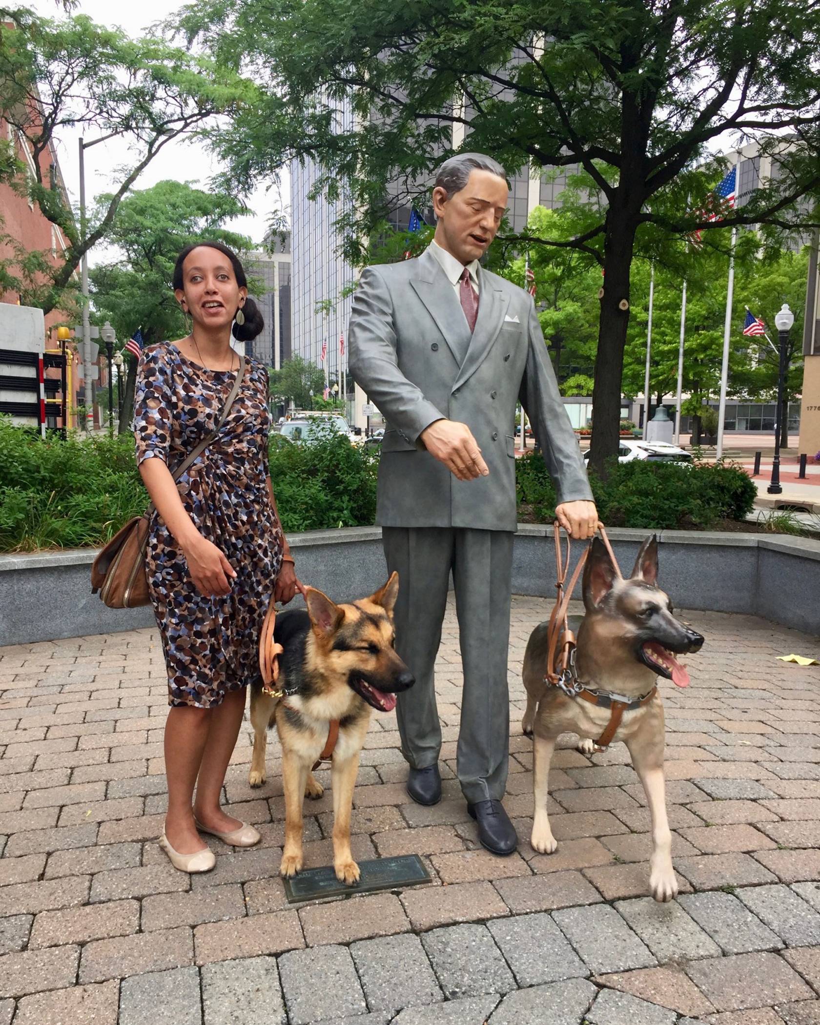 Haben Girma standing by a statue with her seeing eye dog