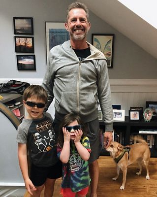 Man standing with his two kids and a dog.