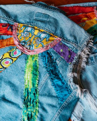 the back of a custom trucker jacket featuring a sun made of different colored fabric