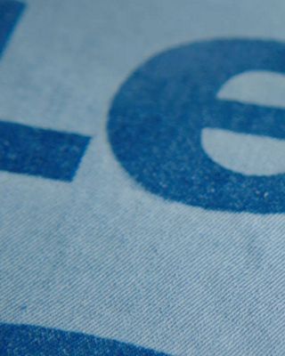 Static image of the Future Finish laser-powered technology, putting light blue Levi's® logo onto a piece of darker wash denim blue fabric.