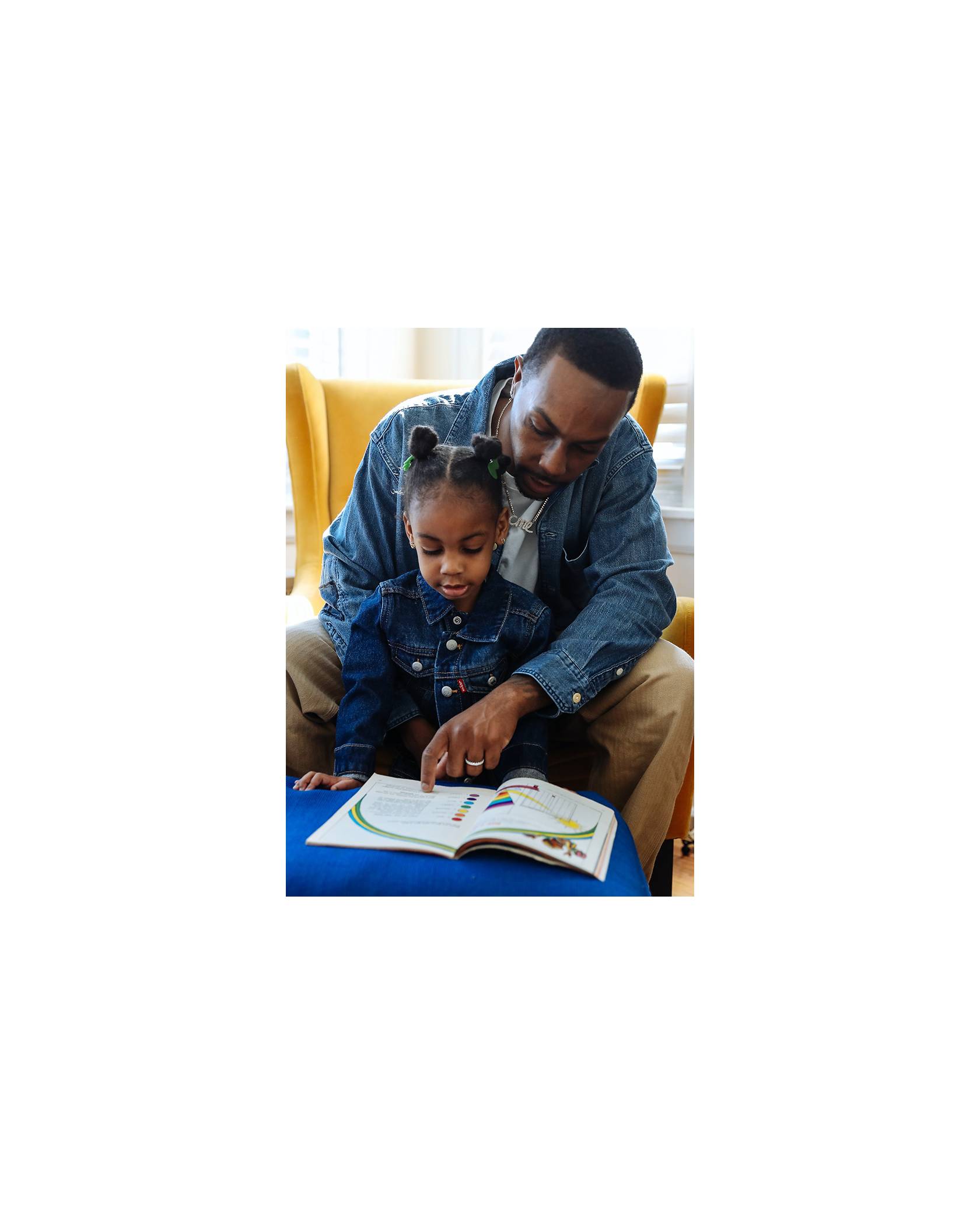 Photo of Adrian Walker reading to his daughter Emory. They are both wearing Levi's Trucker Jackets.