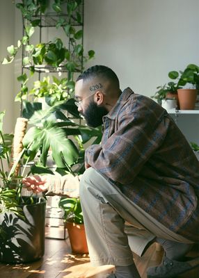 Image of Paul Bellas kneeling next to a row of plants while wearing cargo pants and a Levi's® Made & Crafted plaid brown shirt.