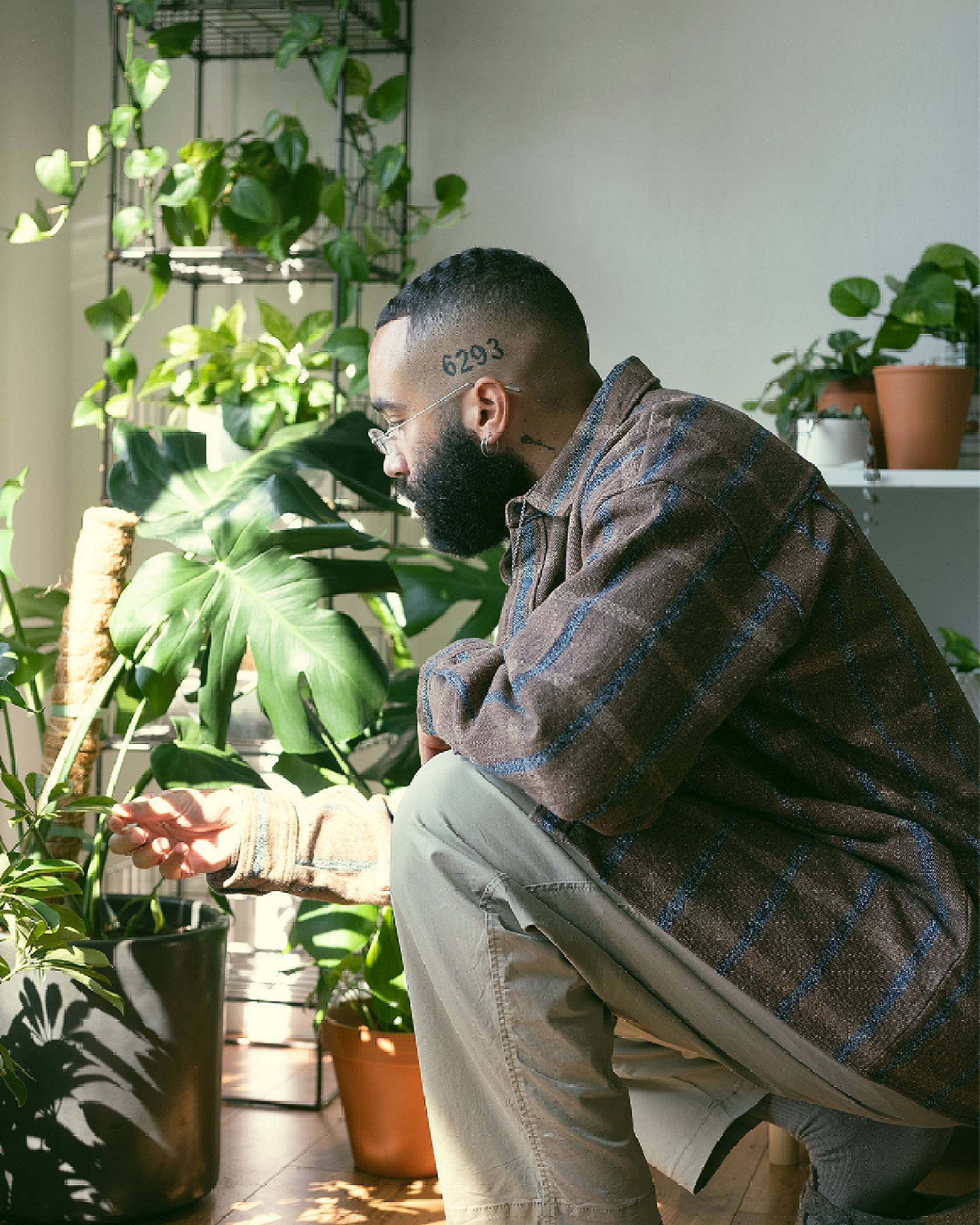 Image of Paul Bellas kneeling next to a row of plants while wearing cargo pants and a Levi's® Made & Crafted plaid brown shirt.