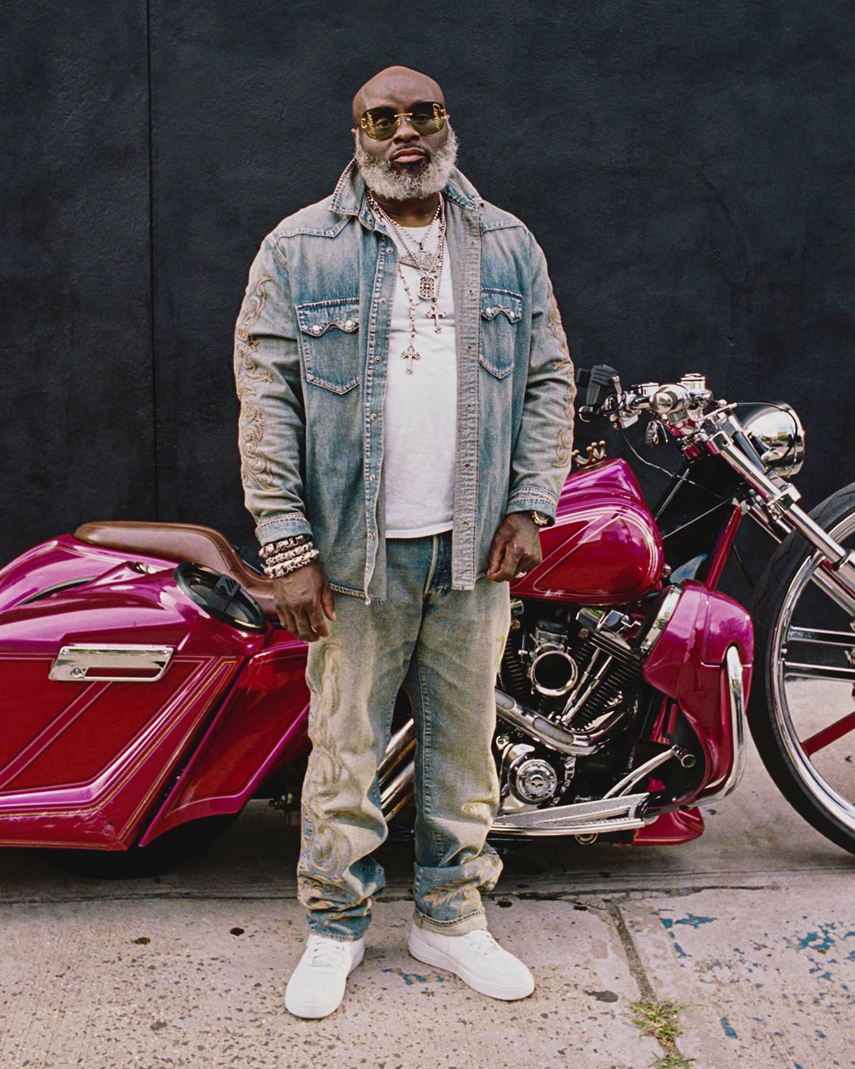 Image of model posing in Levi's x Denim Tears collaboration pieces in front of a red motorcycle.