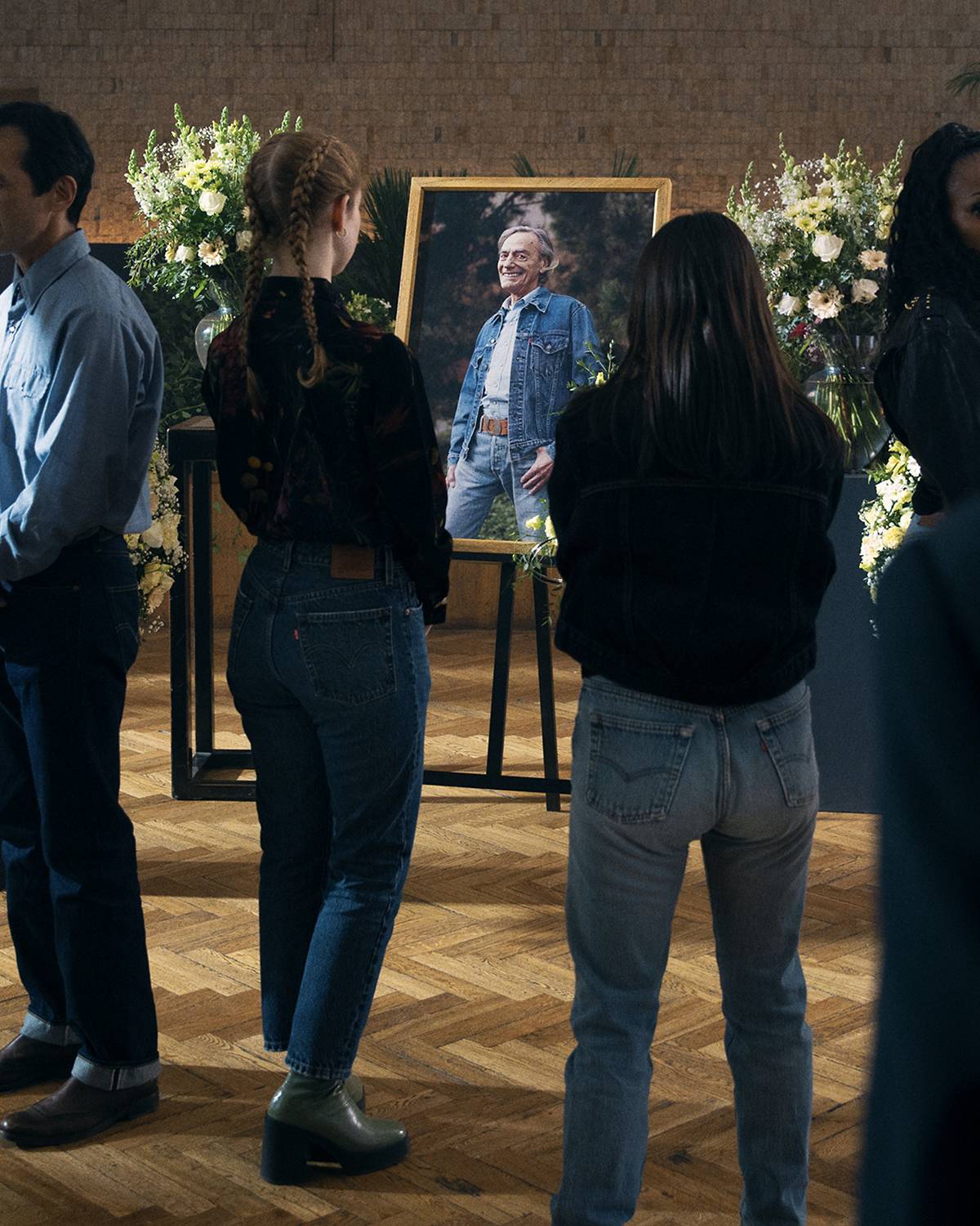 People wearing Levi's jeans at a funeral looking at a picture of the person who passed who is wearing Levi's jeans and a Trucker Jacket.