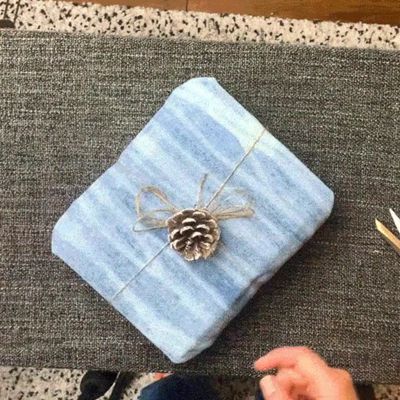 hands adding bows and decorations to denim box