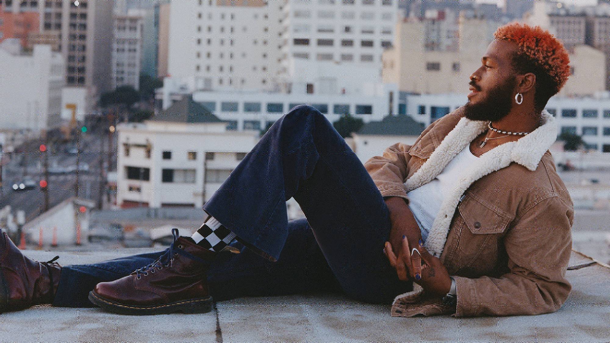 Duckwrth laying on a rooftop with a city view in the background.