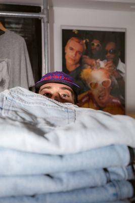 Photo of Sam Trotman peeking out from behind a stack of Levi's jeans.